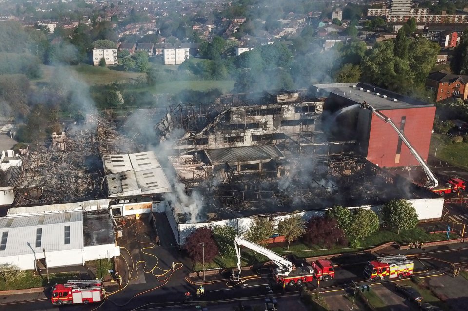 Aerial view of a fire-damaged building with firefighters and fire trucks on scene.