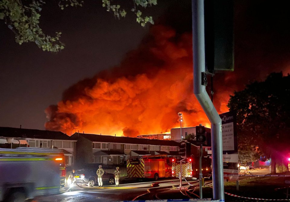 Firefighters battling a large fire at night.