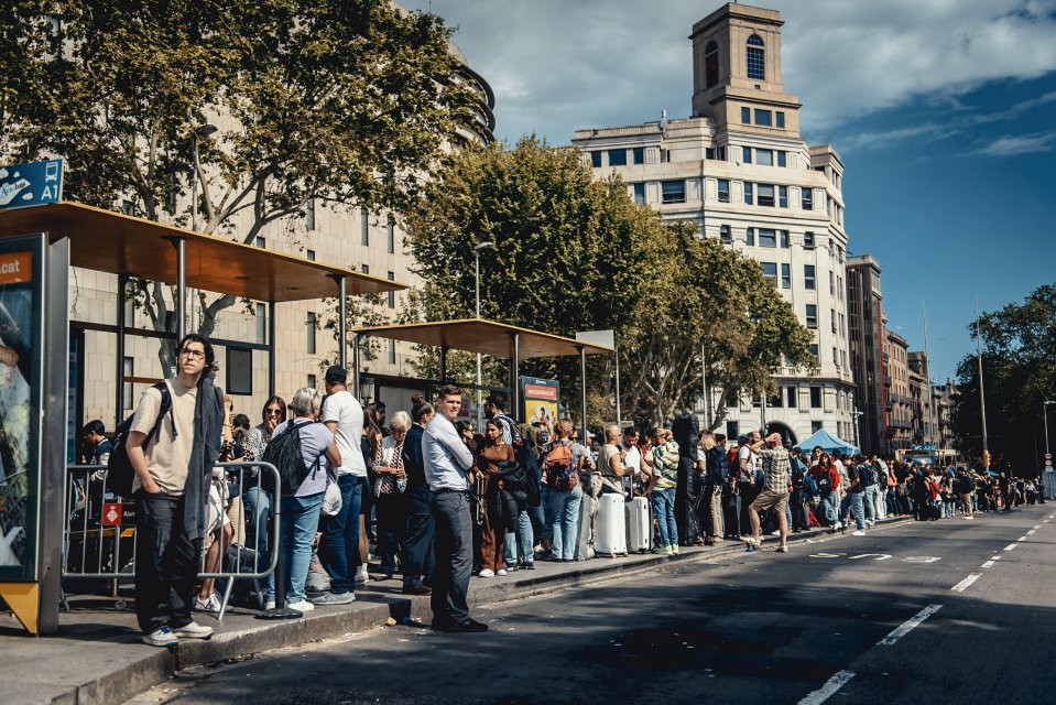 Long queue of travelers waiting for airport transit buses during a power outage in Barcelona, Spain.