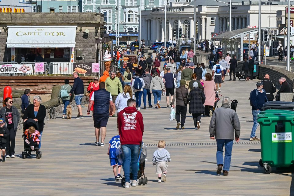 Crowded seafront promenade on a sunny day.