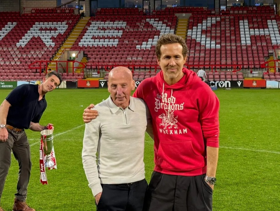 Ryan Reynolds and two other men at a soccer stadium.