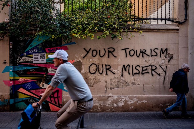 2X23P43 19 April, 2024. Barcelona, Spain: In Barcelona's Gracia Quarter people passes by an anti-tourism graffiti reading 'Your Tourism, Our Misery.' Protests against mass tourism have been going on for years in the Catalan capital, one of the main tourist destinations over the world. Credit: Jordi Boixareu/Alamy Life News