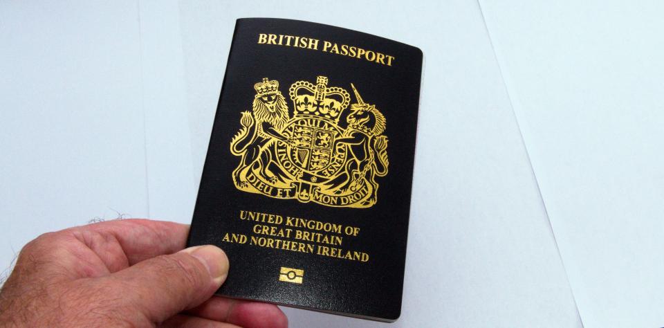 A hand holding a British passport.