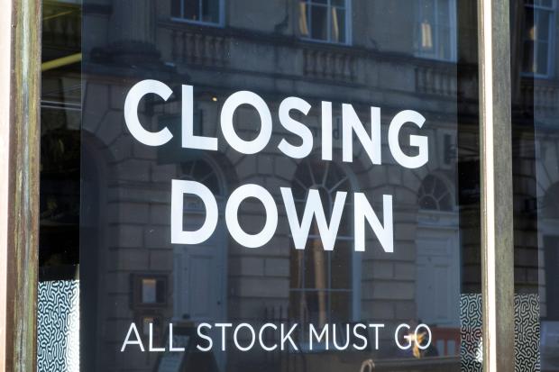 Store window with "CLOSING DOWN, ALL STOCK MUST GO" sign.
