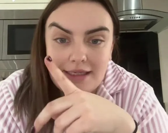 Woman in striped pajamas refuting a comment about traveller site shortages.