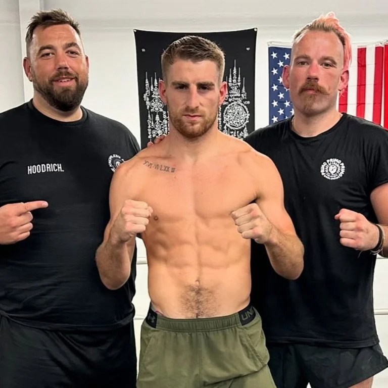 A shirtless fighter flanked by two men.
