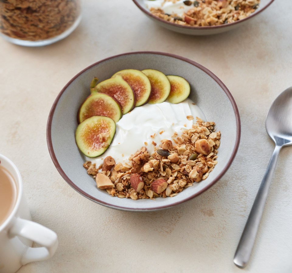 Two bowls of granola, yogurt, and sliced figs.