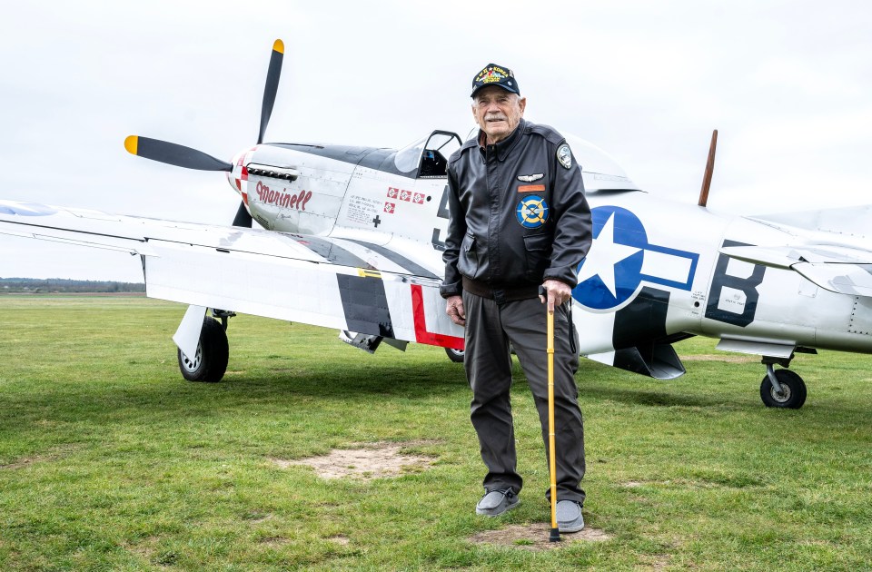 WWII veteran standing in front of a fighter plane.