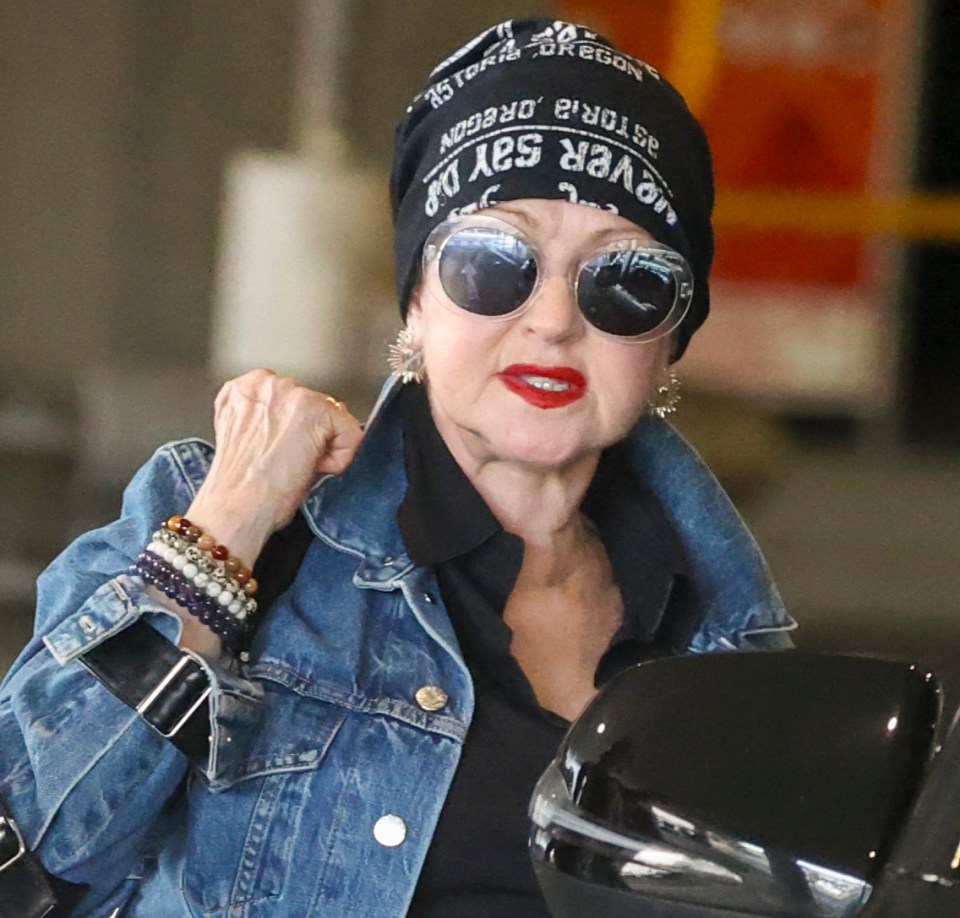 Cyndi Lauper at Sydney Airport wearing a denim jacket and hat.