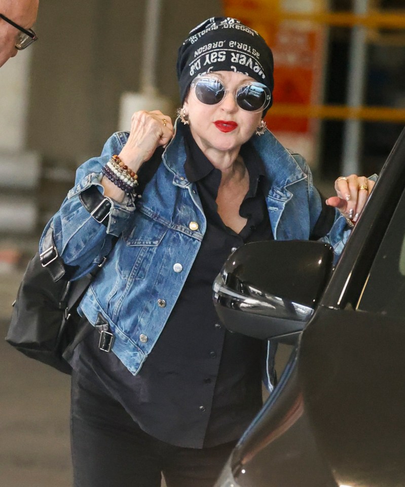 Cyndi Lauper at Sydney Airport wearing a denim jacket and hat.