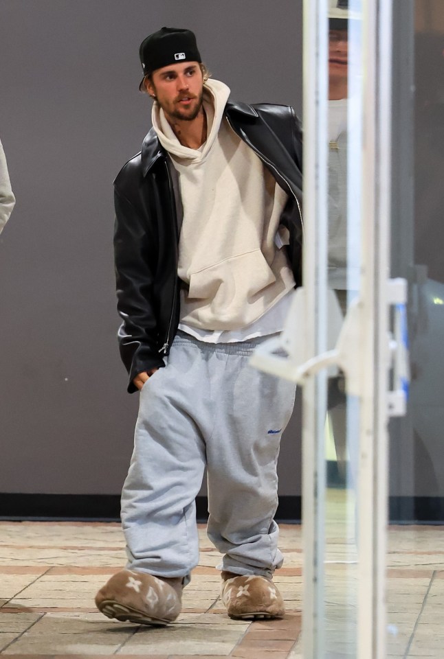 Justin Bieber wearing a black leather jacket, beige hoodie, and gray sweatpants.