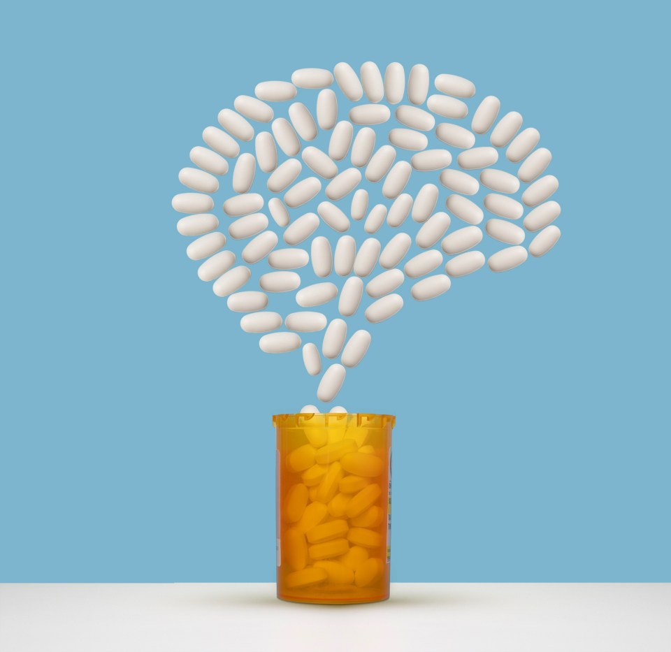 White pills forming a brain shape above a pill bottle.
