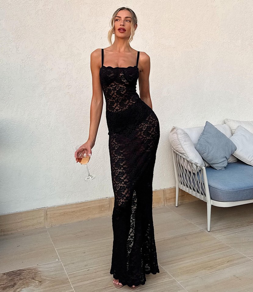 Woman in black lace dress holding a glass of wine.