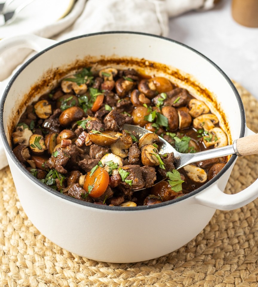 Beef stew with mushrooms in a white pot.