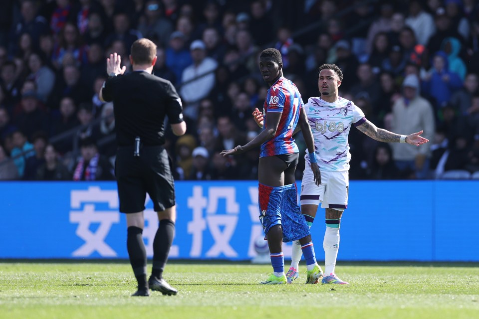 Soccer referee and two players on the field.