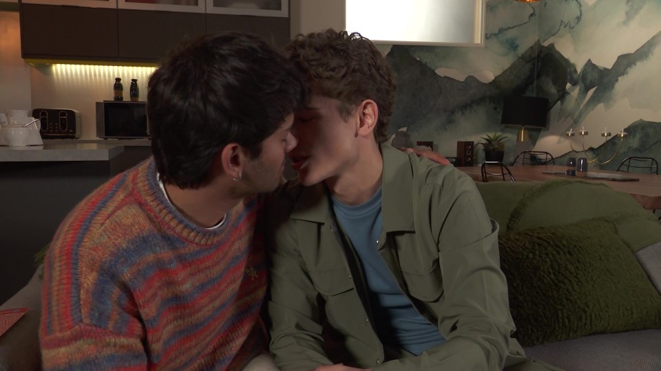 Two men kissing on a couch.