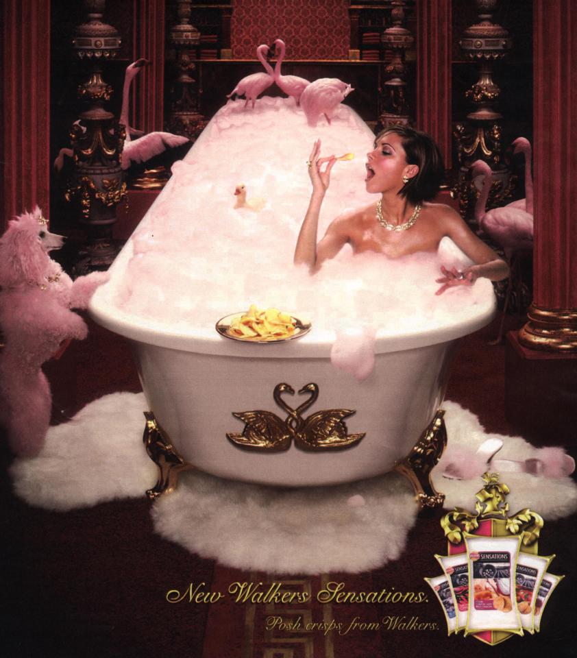 Woman in bubble bath eating crisps with pink flamingos and poodle.