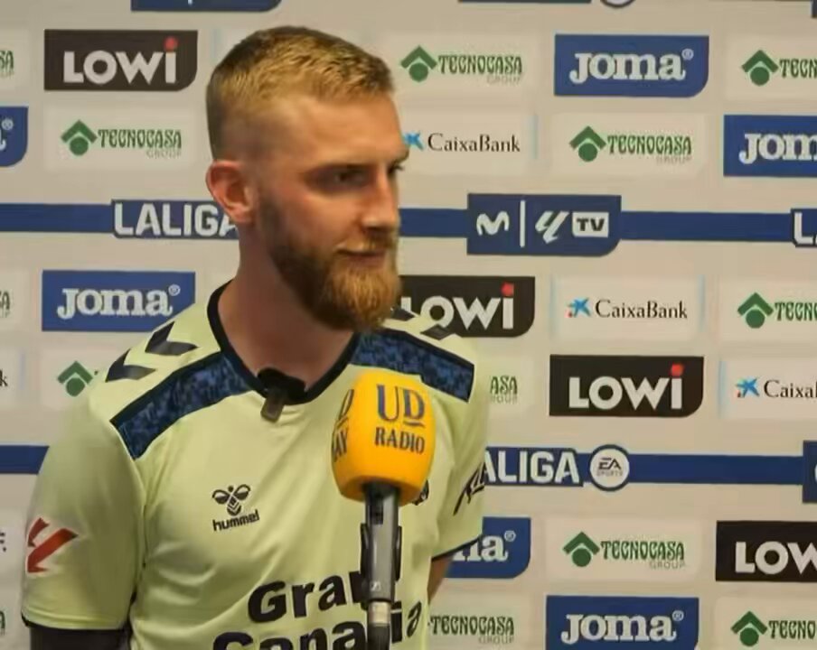 Man in light yellow jersey at press conference.