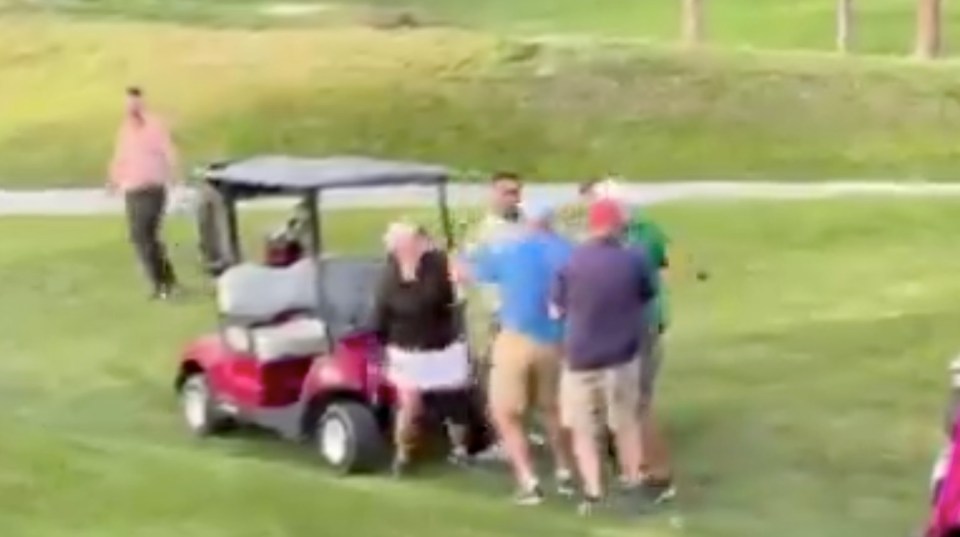A group of people surrounding a golf cart on a golf course.