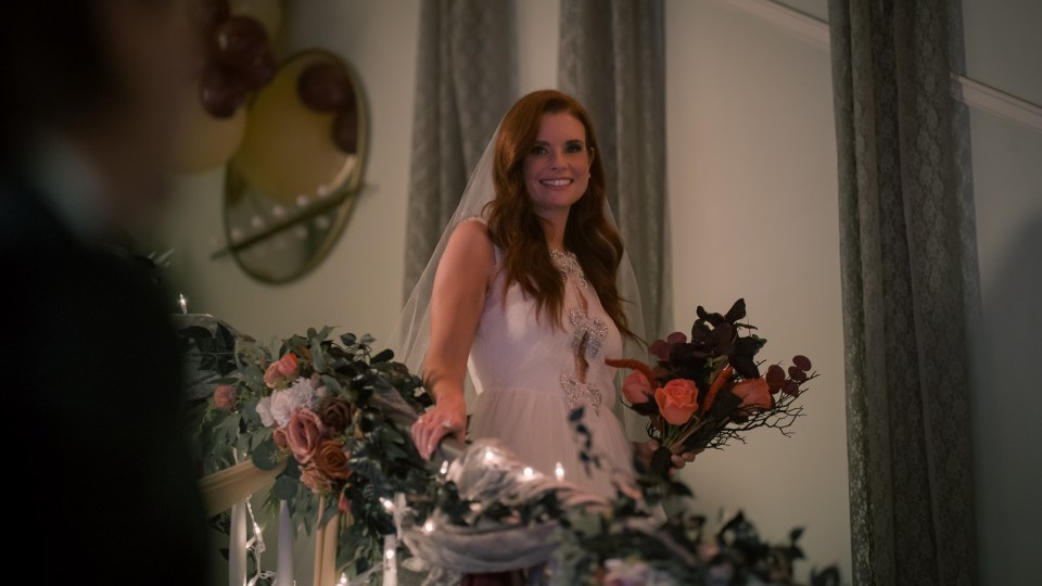 Maddie Townsend, a bride in a white dress, smiles while holding a bouquet.