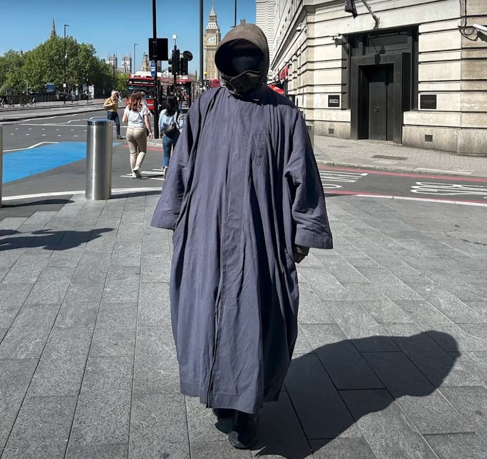Person in a long robe and face covering walking down a city street.