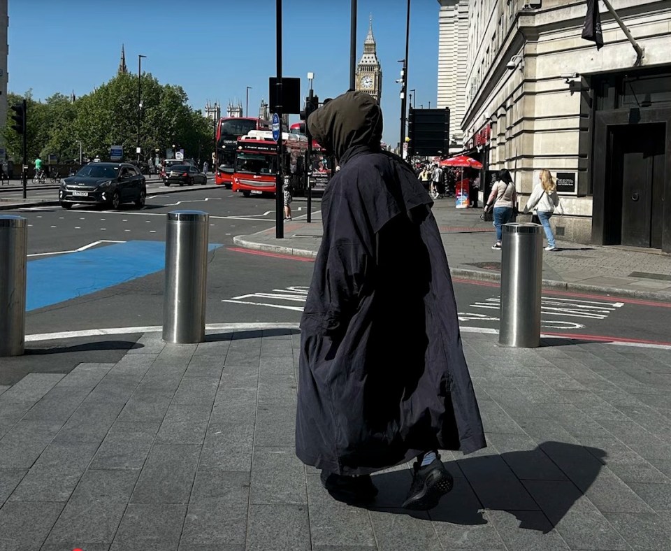 Person in long dark coat walking in London, Big Ben in the background.