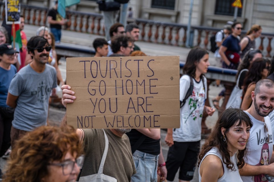 BARCELONA, CATALONIA, SPAIN - 2024/07/06: An anti-tourism placard is seen during the demonstration. More than 3,000 people demonstrated against the tourist overcrowding suffered by the city of Barcelona and in favor of tourism reduction policies. The demonstration involved symbolically closing hotel establishments, bars and restaurants while heading towards Barceloneta, one of the neighborhoods that suffers the most from the presence of tourism. (Photo by Paco Freire/SOPA Images/LightRocket via Getty Images)