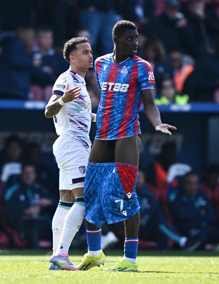 Soccer player with jersey pulled up, arguing with another player.