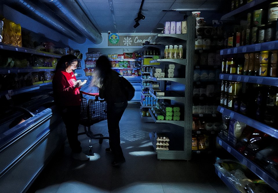 A worker assists a customer with a torch at a supermarket during a power outage which hit large parts of Spain, in Barcelona, Spain April 28, 2025. REUTERS/Nacho Doce TPX IMAGES OF THE DAY
