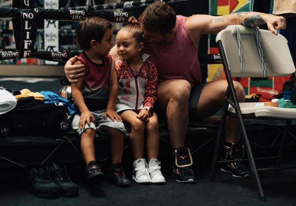 A man sits with two young children.