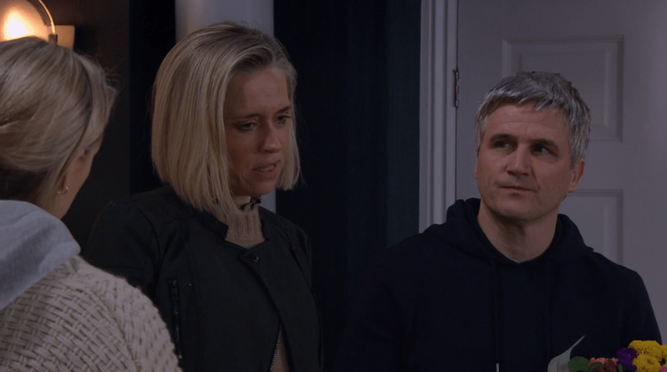 Screenshot of three people, two women and a man, having a conversation.  The man is holding flowers.