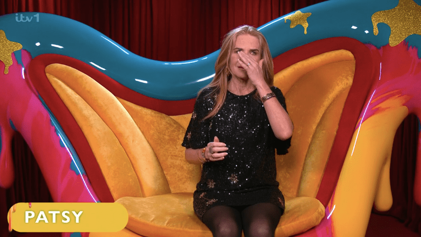 Patsy wiping away tears while sitting in a colorful chair.