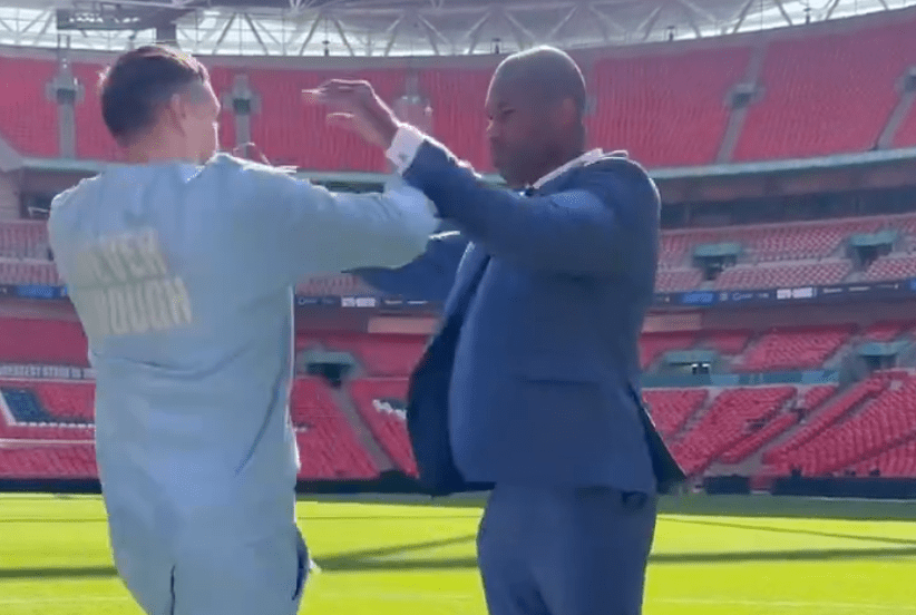 Two men facing each other and playfully sparring in a stadium.