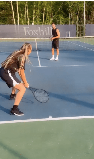 Two people playing tennis on a court.