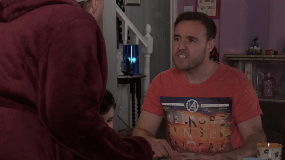 Screenshot of a man arguing with a woman, a child is visible in the background.