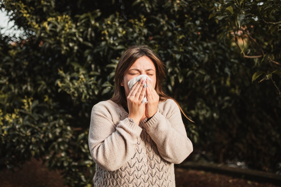 Woman sneezing outdoors.