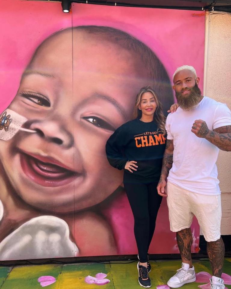 Ashley Cain and Safiyya Vorajee stand in front of a mural of their daughter.