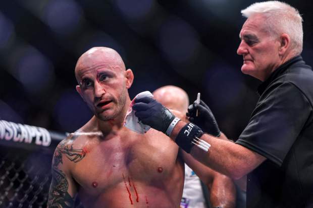 Alexander Volkanovski with blood on his face and chest having it wiped away by a doctor.