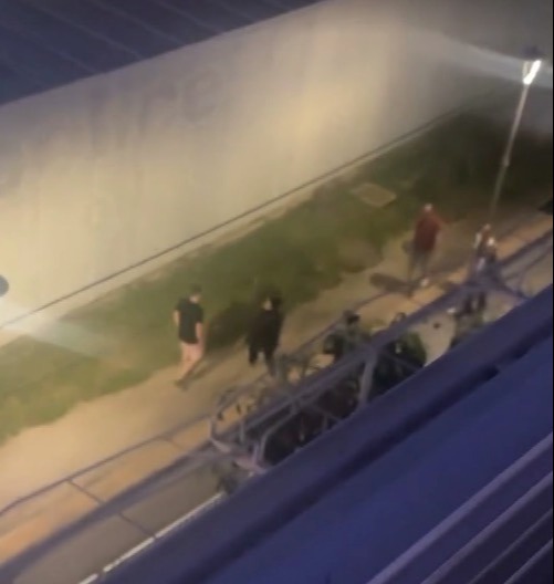 Overhead view of people walking near a vehicle at night.