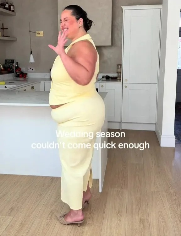 Woman in a pale yellow pantsuit in a kitchen.