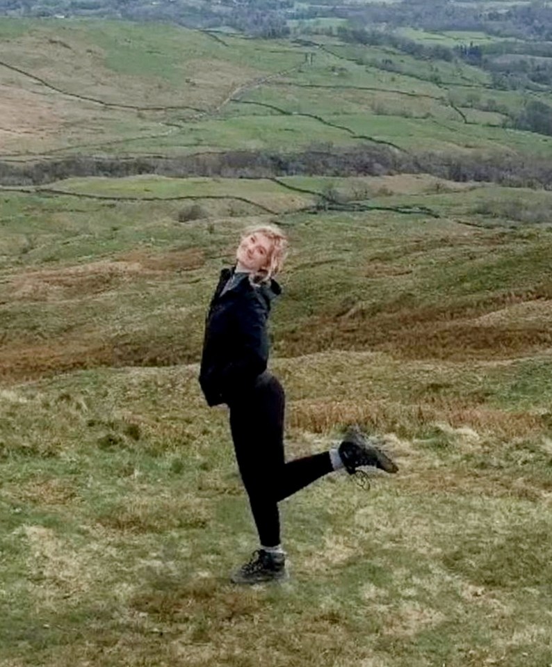 Woman standing in a field, smiling.