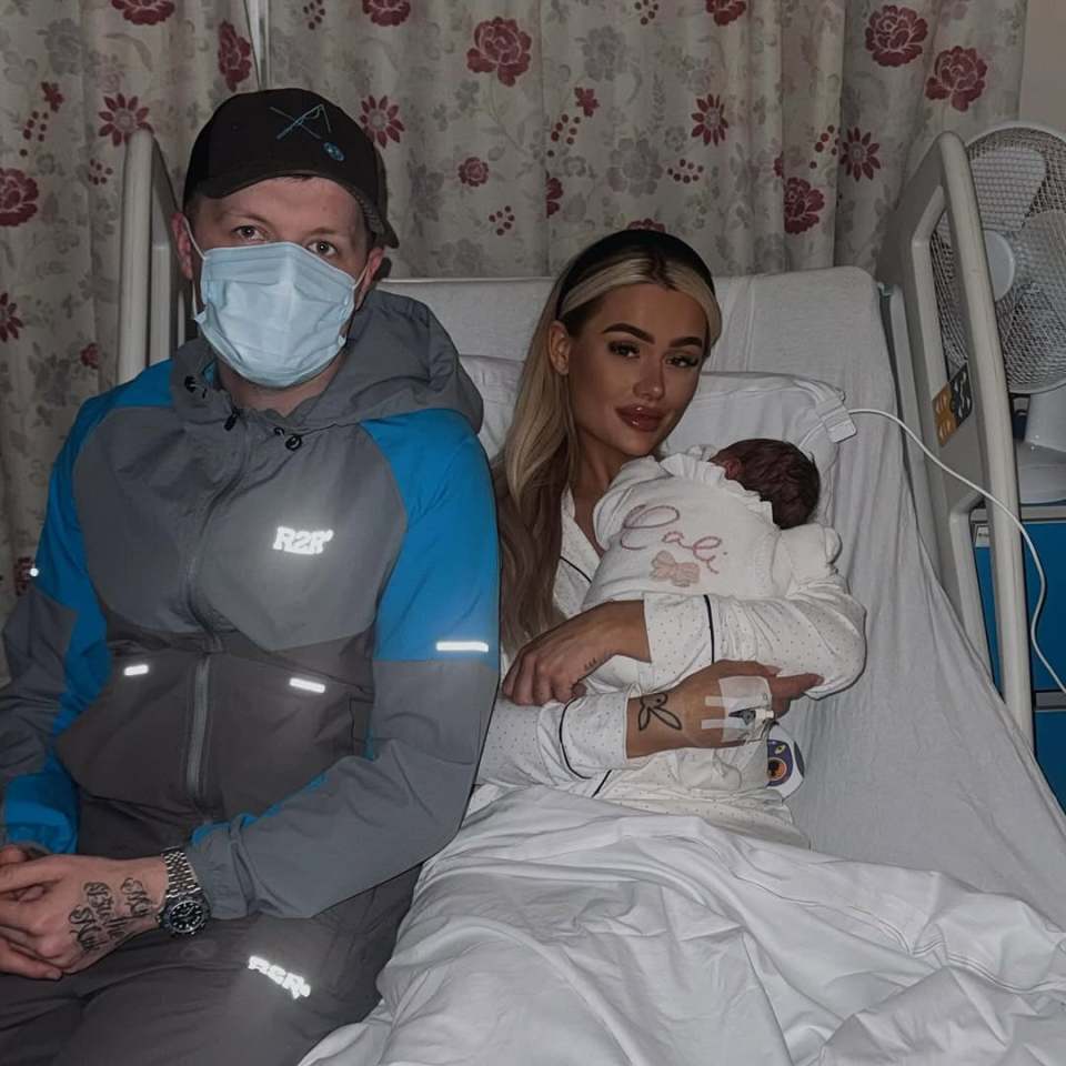 Parents holding their newborn baby in a hospital room.