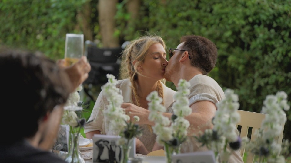 Stacey Solomon and Joe Swash kissing at a table outdoors.