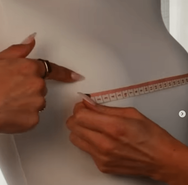 Hands measuring waist with tape measure.