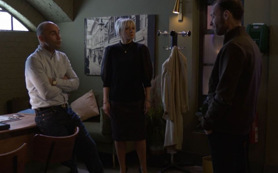 Three people standing in a room, talking.
