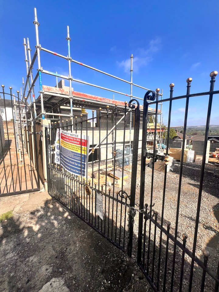 House under construction behind a locked gate.