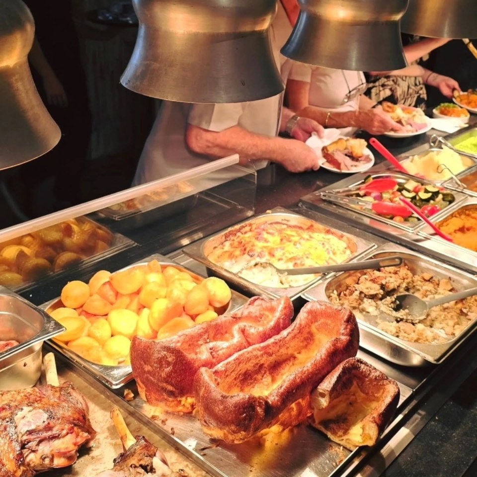 Carvery station with various meats, vegetables, and Yorkshire puddings.
