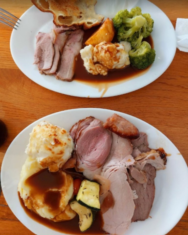 Two plates of roast meat, potatoes, vegetables, and gravy.