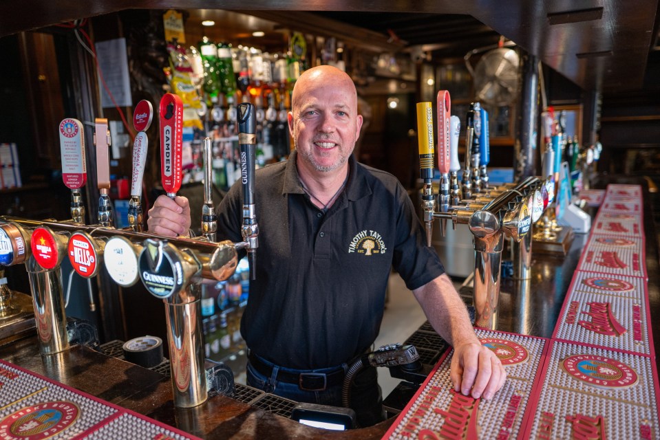Bartender at a pub holding a beer tap handle.