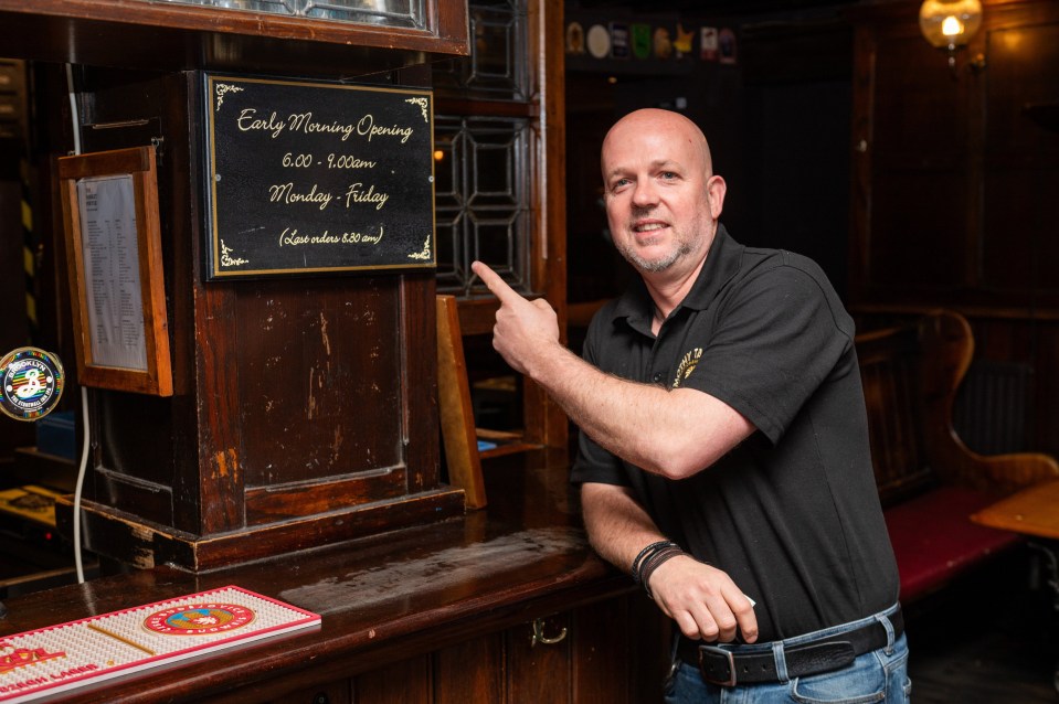 Pub landlord pointing to a sign advertising early morning opening hours.